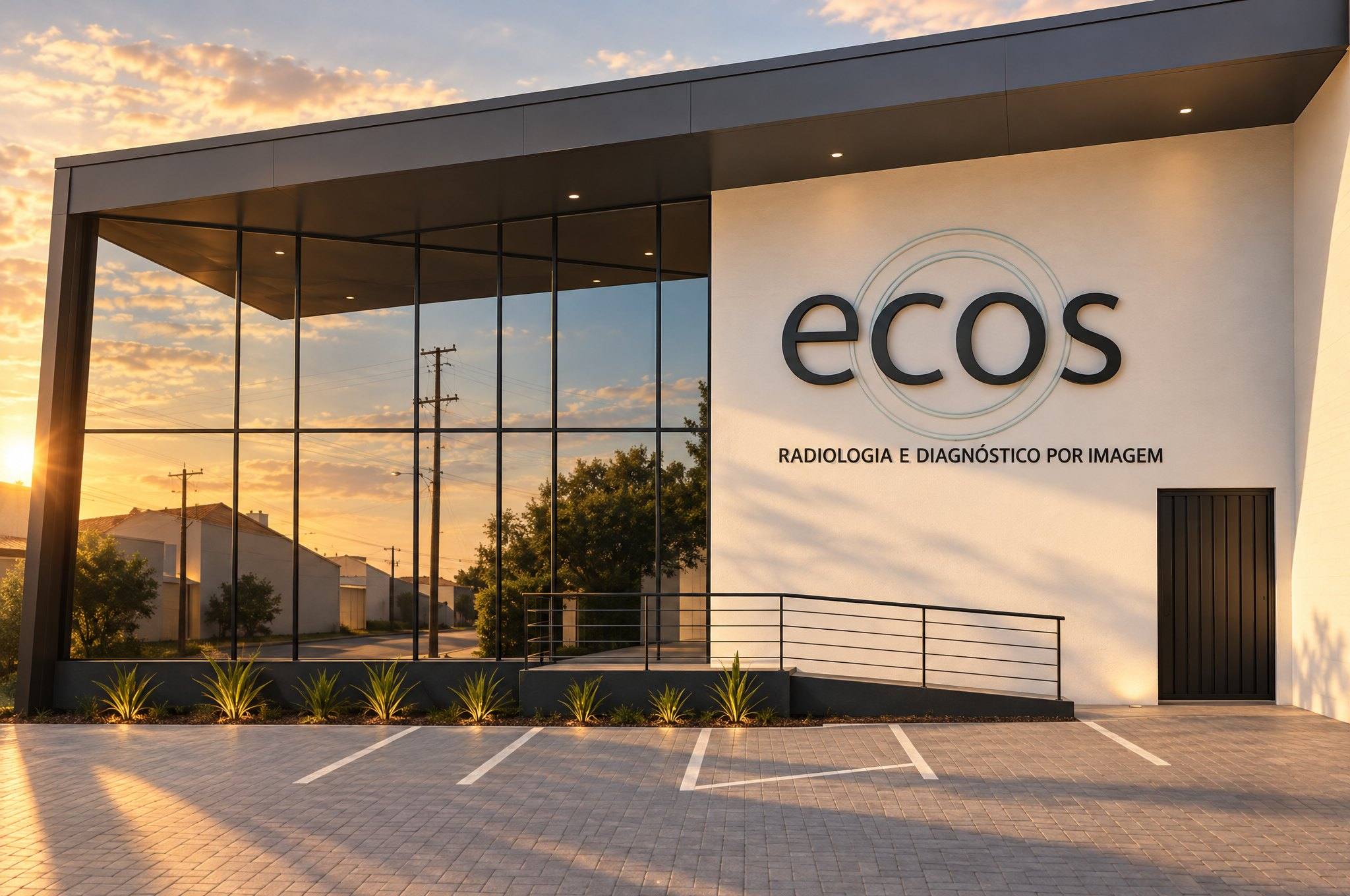 Prédio da Unidade II da ECOS ao fim da tarde: fachada de vidro e parede branca com o logo "ecos".